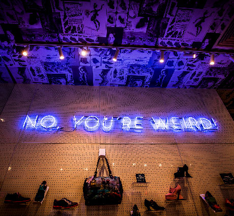 A neon sign inside the Fluevog Melbourne store reads “No, you're weird!”